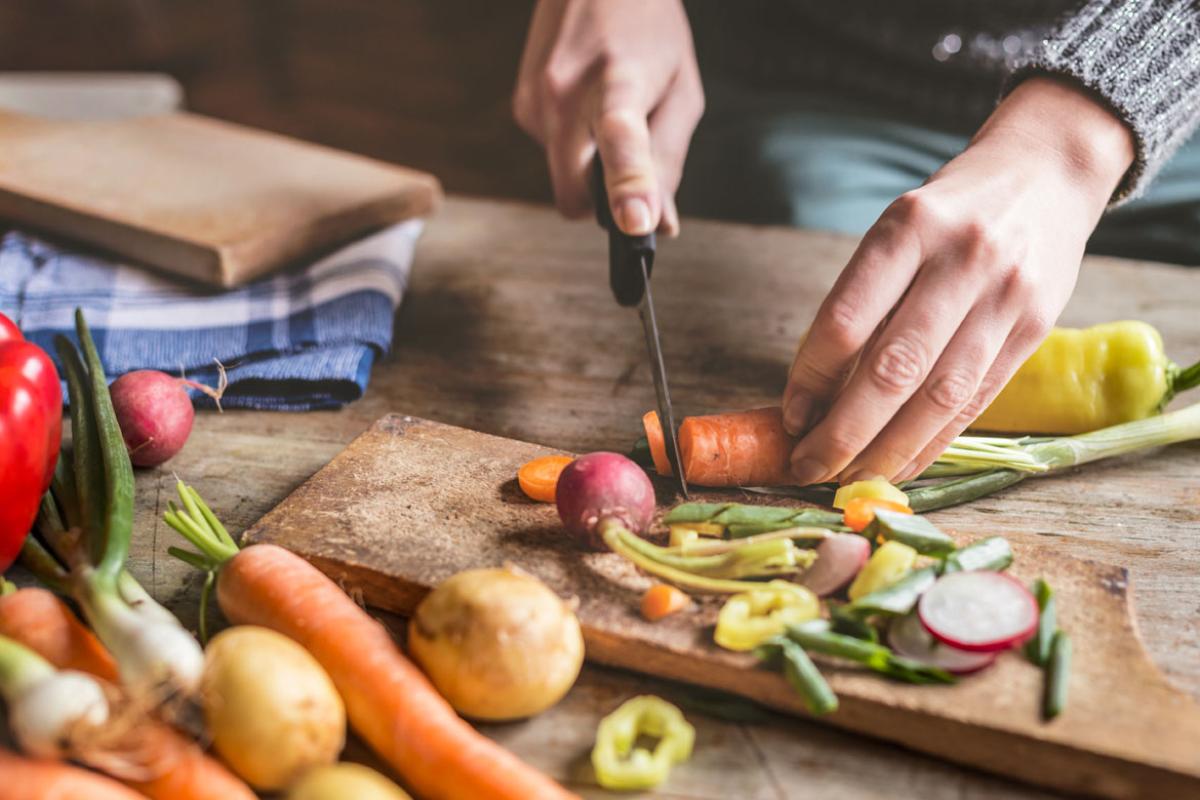 Hands cutting up fresh vegetables.